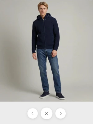 Marinblå sayless cardigan - Säljer en marinblå sayless cardigan med dragkedja framtill och två fickor med dragkedja. Hoodien har en ribbad struktur och en stor huva. Perfekt för dig som gillar en enkel och stilren look. Storlek M och inga tydliga skavanker.