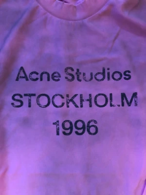 Rosa långärmad topp Acne Studios - Cool rosa långärmad topp från Acne Studios med tryck 'STOCKHOLM 1996' framtill. Rund halsringning och relaxed fit. Perfekt för dig som gillar streetwear och vill ha något unikt från ett svenskt designerbrand.