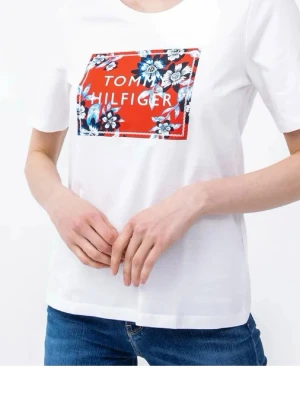 Vit T-shirt Tommy Hilfiger blommig - Vit T-shirt från Tommy Hilfiger med korta ärmar och rund hals. På bröstet finns en stor röd patch med blommigt mönster i blått, vitt och svart samt varumärkets logga. Tillverkad i mjuk bomull, perfekt för en avslappnad och trendig look.