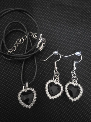 Handgjort Halsband och örhängen med svarta hjärtan - Handgjort Set med halsband och örhängen i form av svarta hjärtan med gnistrande stenar runt om. Halsbandet har ett svart band och silverfärgat spänne. Hjärtana är facetterade och ger en elegant look. Perfekt för dig som gillar unika accessoarer.