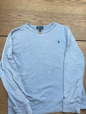 Ljusblå sweatshirt från Polo Ralph Lauren - Hej jag säljer en Ljusblå sweatshirt med rund hals från Polo Ralph Lauren. Tröjan har lång ärm och den klassiska broderade loggan på bröstet. Tillverkad i mjuk bomull för en avslappnad och skön känsla. Den är runt 14-16/XS så klart äkta pris kan diskuteras