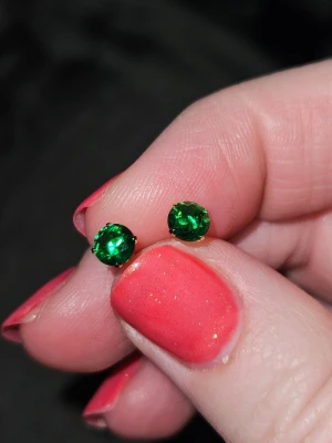 Läckra studsörhängen med grön briljantslipad sten  - Snygga örhängen i form av studs med runda, klara gröna kristaller 4mm. Skruvas. Klassisk och enkel design som ger en färgklick till din look. Metallfästet är diskret och låter de gröna stenarna stå i fokus. Perfekta för dig som gillar stilrena accessoarer.