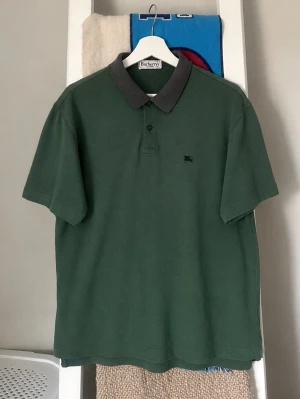 Grön pikétröja från Burberrys - Grön pikétröja från Burberrys. Modellen är vintage men är fortarande i bra skick.