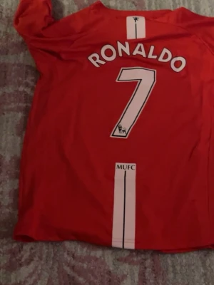 Manchester United Ronaldo tröja - Säljer en röd Manchester United matchtröja med Ronaldo och nummer 7 på ryggen. Tröjan har klubbmärke, Nike-logga och AIG som sponsor på framsidan. Tillverkad i lätt och ventilerande material, perfekt för fotbollsträning eller som supporterplagg.