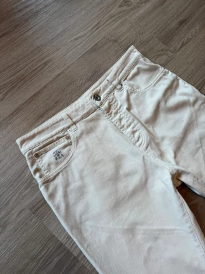 brunello cucinelli jeans  - Säljer ett par vita jeans från brunello cucinelli med klassisk femficksmodell och raka ben. Jeansen har silverfärgade nitar och knapp, samt en liten logga på myntfickan. Perfekta för dig som vill ha en clean och stilren look.