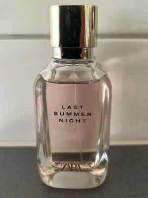 ZARA Last Summer Night parfym - ZARA Last Summer Night parfym i en elegant glasflaska med ljusrosa doftvätska och guldfärgat lock. Flaskan har en stilren, modern design med raka linjer och tydlig text på framsidan. Perfekt för dig som gillar fräscha och somriga dofter.