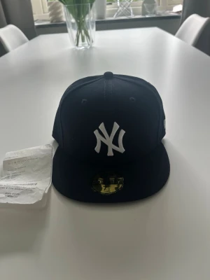 New Era Yankees svart keps 59FIFTY - Säljer en svart New Era 59FIFTY keps med New York Yankees-logga i vitt framtill. Klassisk flat brim och broderade detaljer. Kepsen är helt ny och aldrig använd finns kvitto.