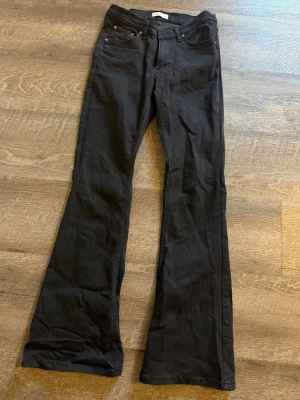 Svarta bootcut jeans - Snygga svarta bootcut jeans med klassisk femficksmodell och utsvängda ben. Jeansen har normal midja och är tillverkade i ett mjukt denimtyg som ger en skön passform. 