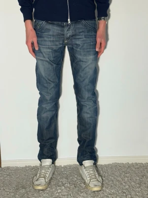 Blå skinny dondup jeans med slitningar - Säljer ett par blå jeans med raka ben och snygga slitningar. Jeansen har klassisk femficksmodell och normal midja. Materialet är denim i bomull och färgen är tvättad blå med ljusare partier. Perfekta för en avslappnad och trendig stil.