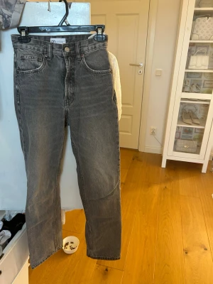 Grå raka jeans från Zara - Säljer ett par gråa raka jeans från Zara med hög midja och. Har inga tecken på användning. Pris kan diskuteras vid snabb affär.