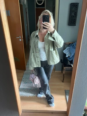 Ljusgrön overshirt med fickor - Stilren ljusgrön overshirt i bomull med klassisk krage och stora bröstfickor. Knäpps framtill med knappar och har en avslappnad passform. Perfekt att slänga över – enkel att styla till olika looks.