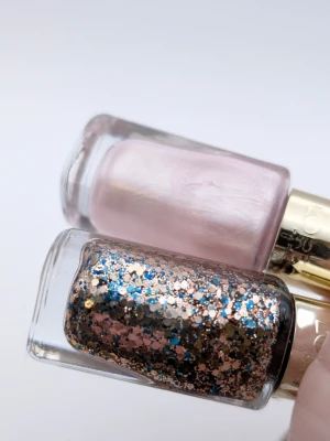 L'Oréal Paris konfetti glitter och pärlemor rosa skimmer ca 70% kvar se bilder - Två nagellack från L'Oréal Paris: ett i ljusrosa pärlemor och ett med glitter i guld, blått och svart. Båda kommer i stilrena glasflaskor med guldfärgade lock. Perfekt för att skapa unika nagellooks med både färg och glitter.