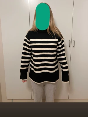 Svartvit randig stickad polotröja - Svart o vitrandig polotröja från hm. Lite orange inuti vid halsen