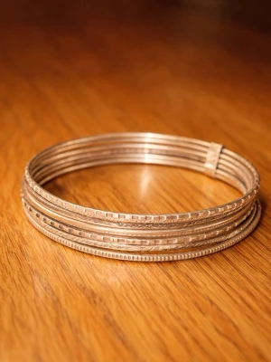 Tunna silverfärgade bangles - Säljer ett set med flera tunna armband i silverfärgad metall. Armbanden har olika mönster och texturer som ger en cool och trendig look. Perfekta att bära tillsammans för en lager-på-lager stil.