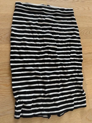 Svartvit randig kortkjol med dragkedja - Säljer en svartvit randig kortkjol med dragkedja längs hela baksidan. Kjolen har en tight passform och är gjord i mjukt bomullsmaterial. Perfekt för dig som gillar en enkel men snygg stil med lite edge.