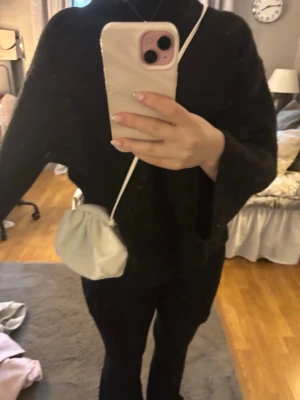 Vit liten axelremsväska i skinnimitation - Säljer en söt vit handväska med axelrem och rynkad design. Väskan har en mjuk, rundad form och är gjord i skinnimitation. Perfekt för dig som vill ha en stilren och trendig accessoar till din outfit. Den har några fläckar på ena sidan. Köpt på Sellpy så vet tyvärr inte märket💞🤗