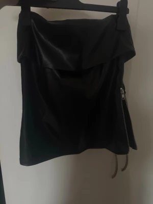 skinn tubtopp - Säljer en svart axelbandslös tubtopp i skinnimitation med dragkedjedetalj på sidan. 