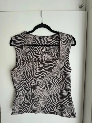 Topp - Säljer en zebramönstrad topp med fyrkantig ringning och breda axelband. Använd en gång 
