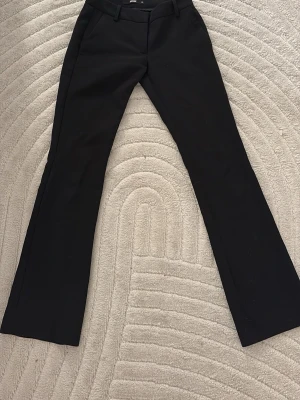 Svarta kostymbyxor från BikBok - Snygga svarta kostymbyxor från BikBok med klassisk rak passform och pressveck. Byxorna har hällor för skärp och diskreta sidofickor. Perfekta för en stilren och trendig look.
