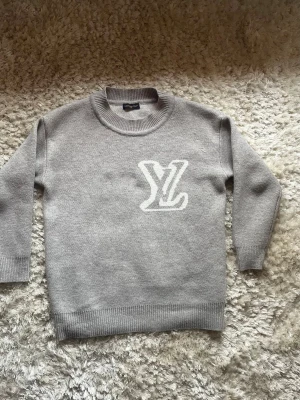 Stickad grå LV tröja - Grå LV tröja med vit märke på! Vid frågor är det bara att skriva, kan tänkas gå ner vid bra bud!