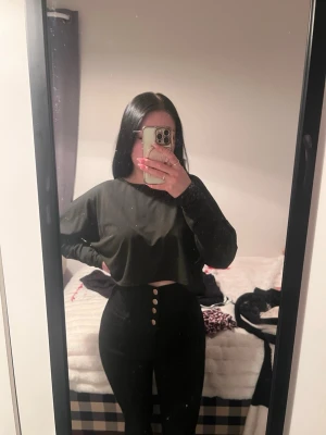 Svarta högmidjade jeans med knappar - Säljer ett par svarta högmidjade jeans med snygga guldknappar framtill. Jeansen har en tight passform och är perfekta för dig som gillar en stilren look. Materialet är klassiskt jeans och de är enkla att matcha med olika toppar.