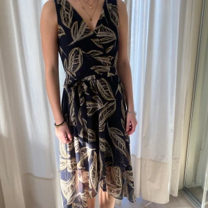 Fin sommarklänning från DKNY, stl S - Fin blommig mörkblå sommarklänning med skärp i midjan, v-ringad fram och blixtlås bak, stl S, från DKNY.