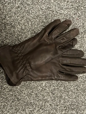 Br UVa bruna skinnhandskar - Snyle bruna handskar i mjukt skinn med klassisk design och längre skaft. Perfekta för kyliga dagar daylight och ger en stilren look. Handskarna har diskret resår vid handleden för bättre pass flim.