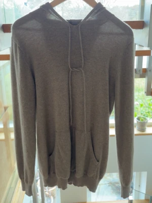 John Henric Kashmir hoodie  - Mysig beige hoodie med huva och dragsnören. Har en stor känguruficka framtill och ribbade muddar vid ärmslut och nederkant. Tillverkad i mjukt stickat material som känns skönt mot huden. Perfekt för chill dagar eller när du vill ha en enkel och stilren look. Använd ett fåtal gånger. Nypris 2999.
