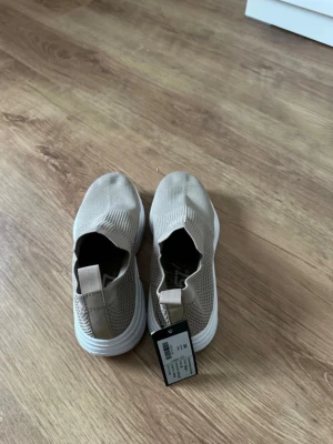 Nya beige sneakers slip-on – stl 36 - Helt nya sneakers från Lager 157 i storlek 36. Lappen sitter kvar. Väldigt lätta och bekväma slip-on skor i stretchigt material som är enkla att ta på. Perfekta till vardag eller som sommarskor.