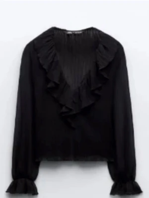 Svart volangblus från Zara  - Stilren svart blus med djup v-ringning och bred volangkrage. Knappt använd och i väldigt bra skick..