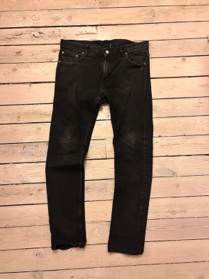 Svarta slim fit jeans med slitningar - Säljer ett par svarta slim fit jeans med diskreta slitningar på knäna och klassiska femficksdetaljer. Jeansen har raka ben och kontrastsömmar. Perfekta för dig som gillar en cool och avslappnad stil.