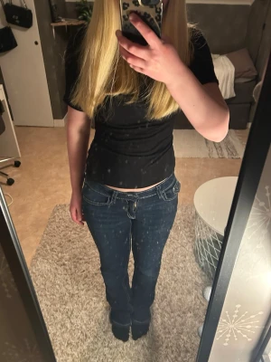 Mörkblå bootcut jeans med kontrastsömmar virtual - Säljer ett par mörkblå boot ent jeans med vita kontrastsömm sop och låg krage. Jeansen har fickor fram och bak, bakfickorna har lock och knappdetalj. Klassisk femficksmodell domest i stretchigt denimtyg. Har gått sönder lite längst ner