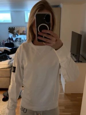 Vit sweatshirt från Ck - Säljer en vit sweatshirt från CK med en svart logga som sitter på vänster ärm. Slapp passform med ribbade muddar på ärmar och nedtill.
