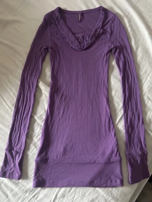 Lila långärmad klänning  - Långärmad klänning i en snygg lila färg  bestående av mjukt och stretchigt material. Modellentrue är figurnära och enkel, perfekt att styla lager på lager eller bära som”: den är. Passar dig som gillar minimalistisk stil.
