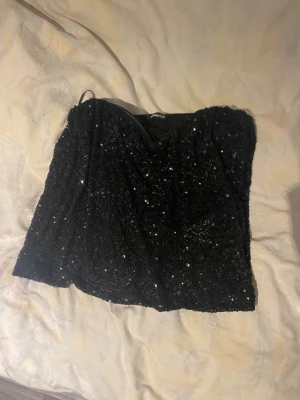 Svart paljett tubtopp från Gina Tricot - Säljer en svart tubtopp från Gina! Den är perfekt nu till nyår och har bara använts 1 gång🤍 Den är slutsåld på hela hemsidan och i butik i denna storlek! 