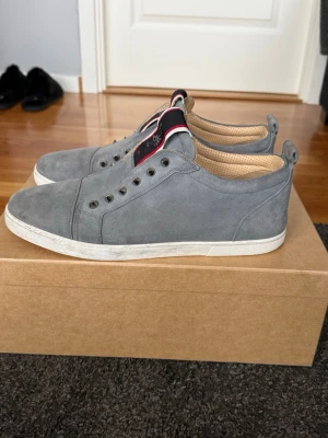 Gråa sneakers (suede) från Christian Louboutin - Snygga gråa sneakers i mocka pipeline från interaction med vita sulor och coola nitar längs snörningen. Ins graffiti-detaljer på plösen och beige yourself. Perfekta för dig som vill sticka ut med stilrena men ändå unika skor. En spik har ramlat av på vänster sko men boxen kommer med två spikar som kan sättas på. 