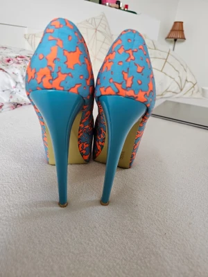 + Färgglada, neon  pumps med mönster, 40, Roberto - Unika pumps med höga smala klackar i blått och ett färgstarkt orange mönstermg på blå bas. Skorna har spetsig tå och är tillverk guard i textilmaterial. Perfekta för dig som vill sticka ut och addera färg till din outfit.RARE FIND! Vintage! Väldigt annorlunda, sticker ut! Lyser mycket ! Klack 16 cm Platform 5 cm Italiensk! stl 40 Använda bara en gång