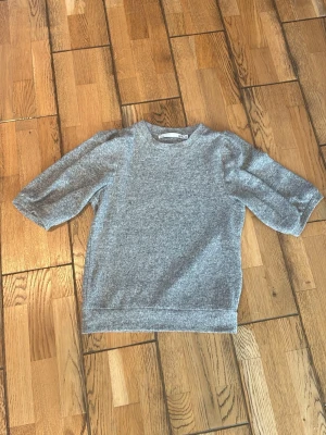 Grå tröja med lite puffärmar  - Jag säljer en grå tröja med lite puffärmar i mjuk material. Säljer pågrund av att den ej används. Tröjan är i storlek xs från lager 157. 