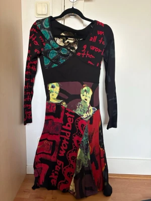 Färgstark långärmad klänning - Unik långärmad klänning med färgstarka tryck, grafiska mönster och textdetaljer. Perfekt för dig som gillar att sticka ut.