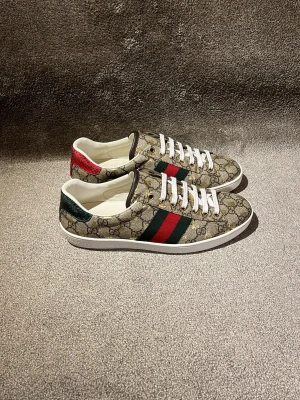 Gucci Ace monogram gold bee  - Hej! Säljer dessa sjukt fräscha och feta Gucci Ace monogram gold bee! Kvaliteten på dessa är otroligt bra och inga defekter förekommer! Skorna är köpta i Gucci butiken för mindre än ett år sedan av min brorsa utomlands i Frankrike och åkte flyg tur och retur och därför saknas både box och kvitto för att undvika tull osv. Skorna är självklart äkta vilket jag står för och det är även olagligt att sälja märkeskopior! Allt på sista bilden medföljer! Nypris 9000kr! Mvh DS ♦️