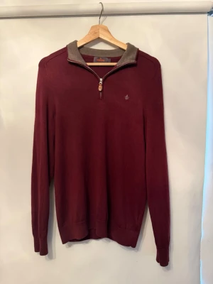 Vinröd merinoullströja från Morris - Snygg vinröd tröja från Morris i 100% merinoull. Tröjan har halv dragkedja, ribbade muddar och kontrastfärgad krage i grått. Perfekt för dig som gillar klassisk men modern stil.