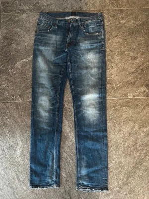 Tiger of Sweden Jeans  - Ett par klassiska blå jeans med snygga tvättade detaljer på både fram- och baksida. Jeansen har fem fickor och raka ben. Perfekta för en avslappnad och trendig look. Säljer därav jeansen har blivit för små för mig.                     Midjemått=39cm.       innerbenslängd=81cm                            Midjan neråt=109,5cm                                OBS kan gå ner i pris vid snabb affär 😊