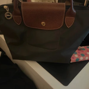 Grå handväska från Longchamp - Mörk Grå handväska i storlek S med korta handlebars, aldrig använd var en present, fint skick, inga skador 