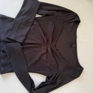 Svart ribbad topp  - Snygg svart långärmad topp från Romwe med ribbad struktur och rynkad detalj framtill. Använd en gång, helt som ny.