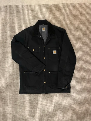 Carhartt Jacka  - Säljer nu den ultimata Carhartt vår/höst jackan pga storlek. Jackan är fodrad och har en snygg krage i Manchester tyg. Det ända som är minus är skadan på innersidan (bild 4), som varken känns eller syns från utsidan. Nypris ligger mellan 1500-2000kr