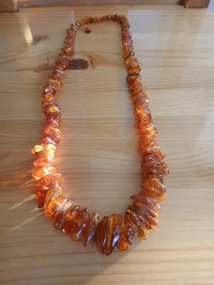 Bärnstenshalsband med oregelbundna pärlor - Unikt halsband med oregelbundna bärnstenspärlor i varma gyllene och bruna toner. Pärlorna är trådade tätt och ger ett naturligt, bohemiskt intryck. Perfekt för dig som gillar naturmaterial och vill sticka ut med ett smycke som fångar ljuset snyggt.