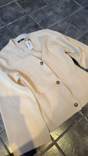 Cardigan från Gina - Figursydd cardigan från Gina, ny med prislapp kvar.