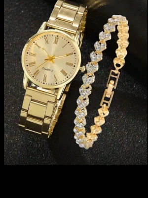 Guldig klocka med länkarmband - Stilren guldig klocka från Quartz med klassisk länkdesign och urtavla med romerska siffror. Klockan har en elegant metallfinish och passar perfekt för dig som gillar en lyxig look. Säljes tillsammans med ett matchande armband med gnistrande stenar.