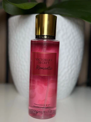 Victoria's Secret Romantic mist - En rosa doftmist från Victoria's Secret med namnet Romantic. Flaskan är genomskinlig med guldigt lock och rymmer 250 ml. Perfekt för dig som gillar fräscha och blommiga dofter i en snygg och stilren förpackning.