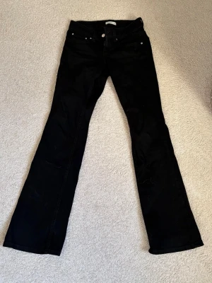 Svarta bootcut jeans från Gina Tricot - Säljer ett par svarta bootcut jeans från Gina Tricot. Jeansen har klassisk femficksmodell, silverfärgade knappar och detaljer samt utsvängda ben. Perfekta för dig som gillar en tidlös och trendig look. Det finns svaga tecken på slitage längst ner vid benen men inga hål! Skriv pm vid funderingar!😊